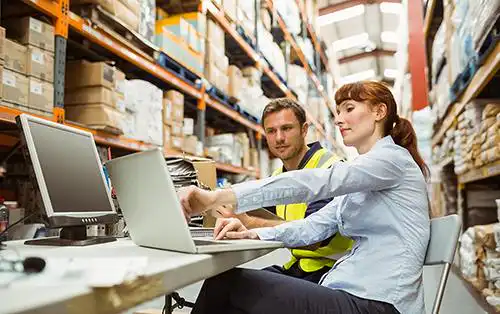 Warehouse worker and manager looking at laptop
